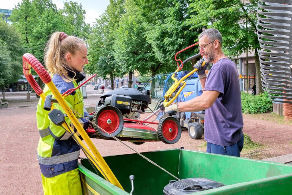 Summer workers lifting garden tools in a park in Kotka.