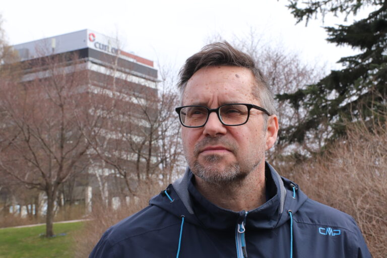 Mies katsoo horisonttiin lähikuvassa, taustalla näkyy Karhulan Eagle-talo.