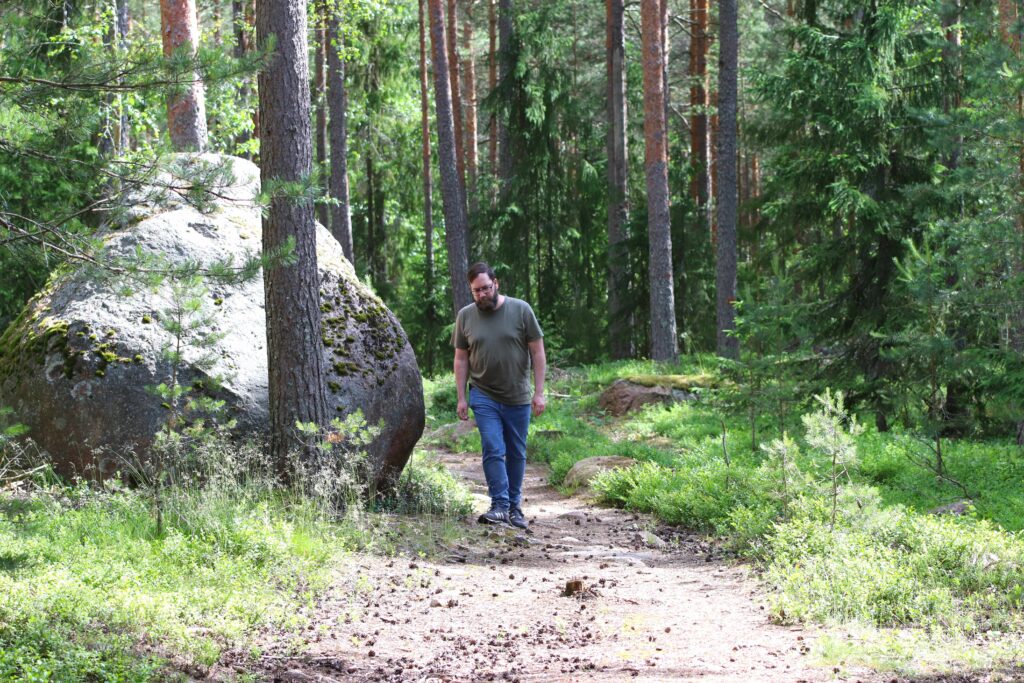 The man is walking on a forest trail.