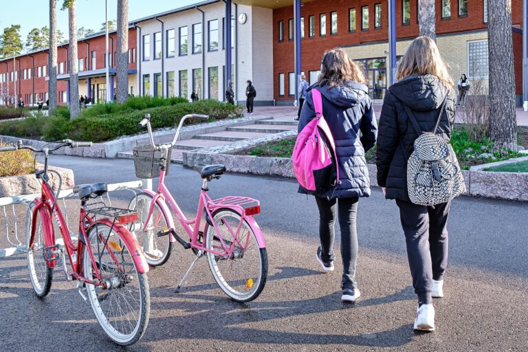 Kaksi opiskelijaa kävelee kohti koulurakennusta.